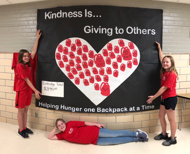 Photo of students holding a banner that says "Kindness is Giving to Others"